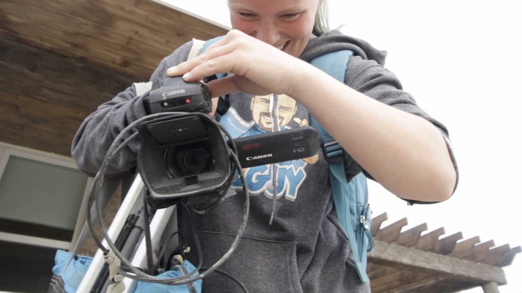 katie is on the job site with a video camera in her hand and she is smiling