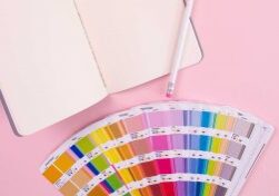 a journal and a pencil are on a pink background with pantone color chips